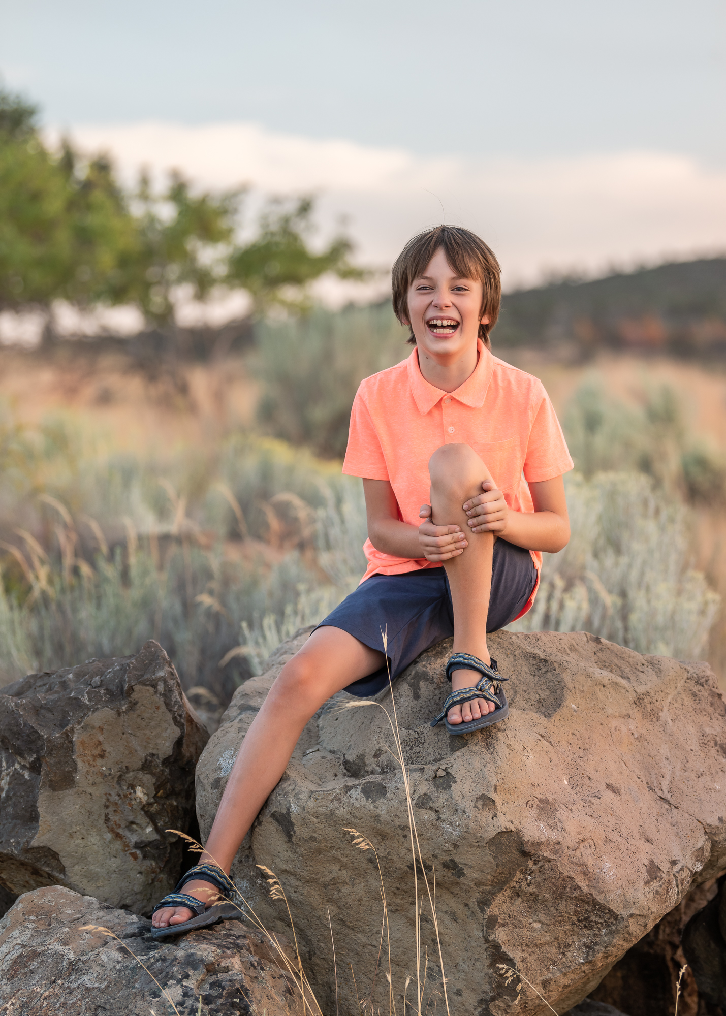 Boy laughing and sitting on a rock The Hanger Boutique in Klamath Falls