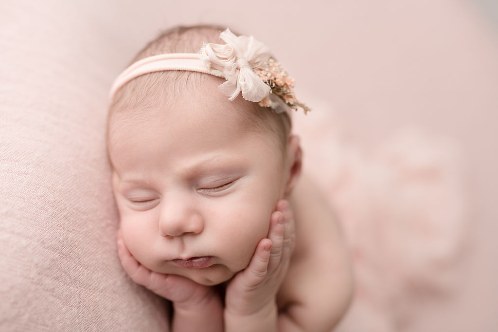 newborn baby girl with her head resting on her hands in all pink Ashland Birth Center