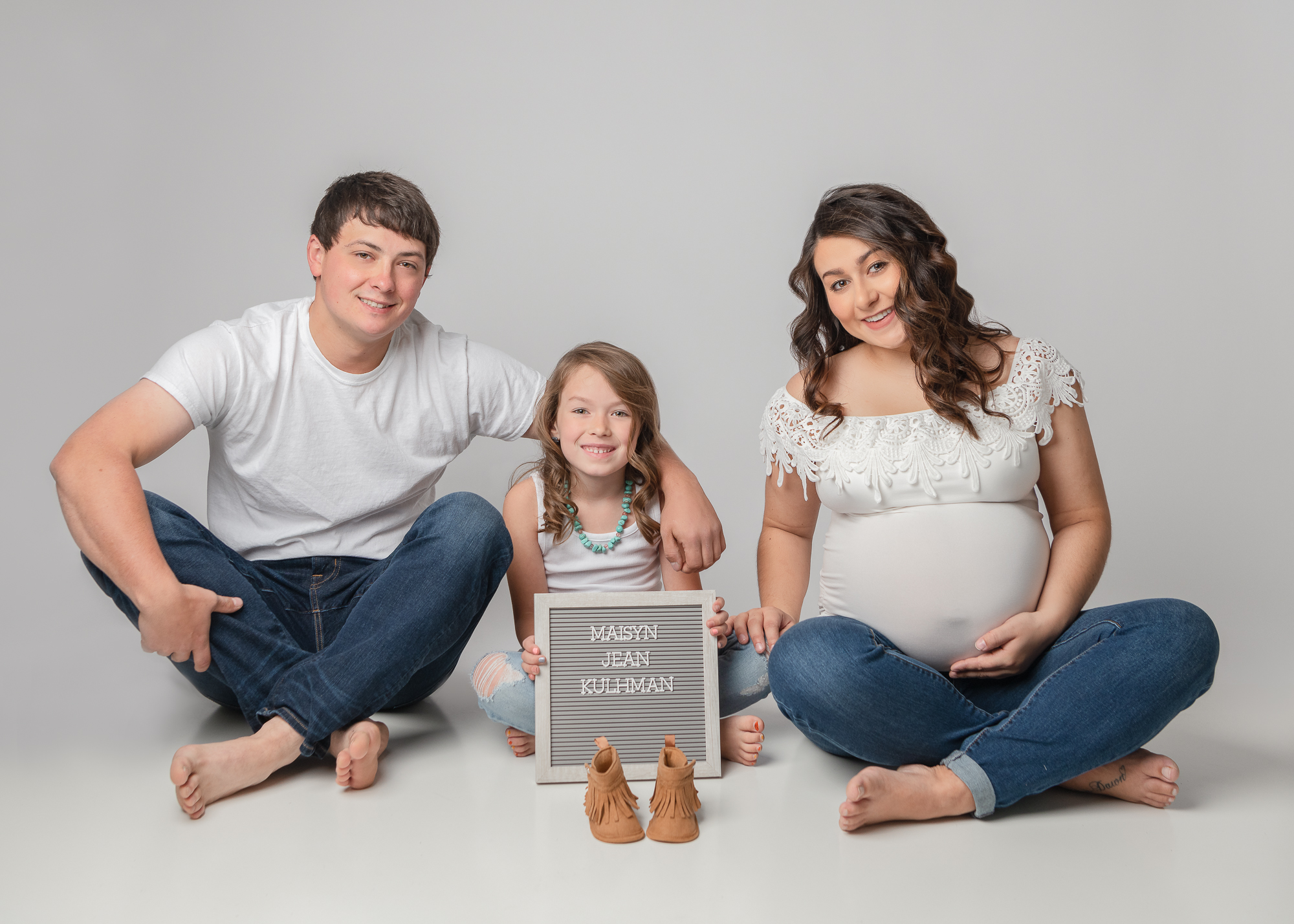 Family expecting a new baby sitting on the floor