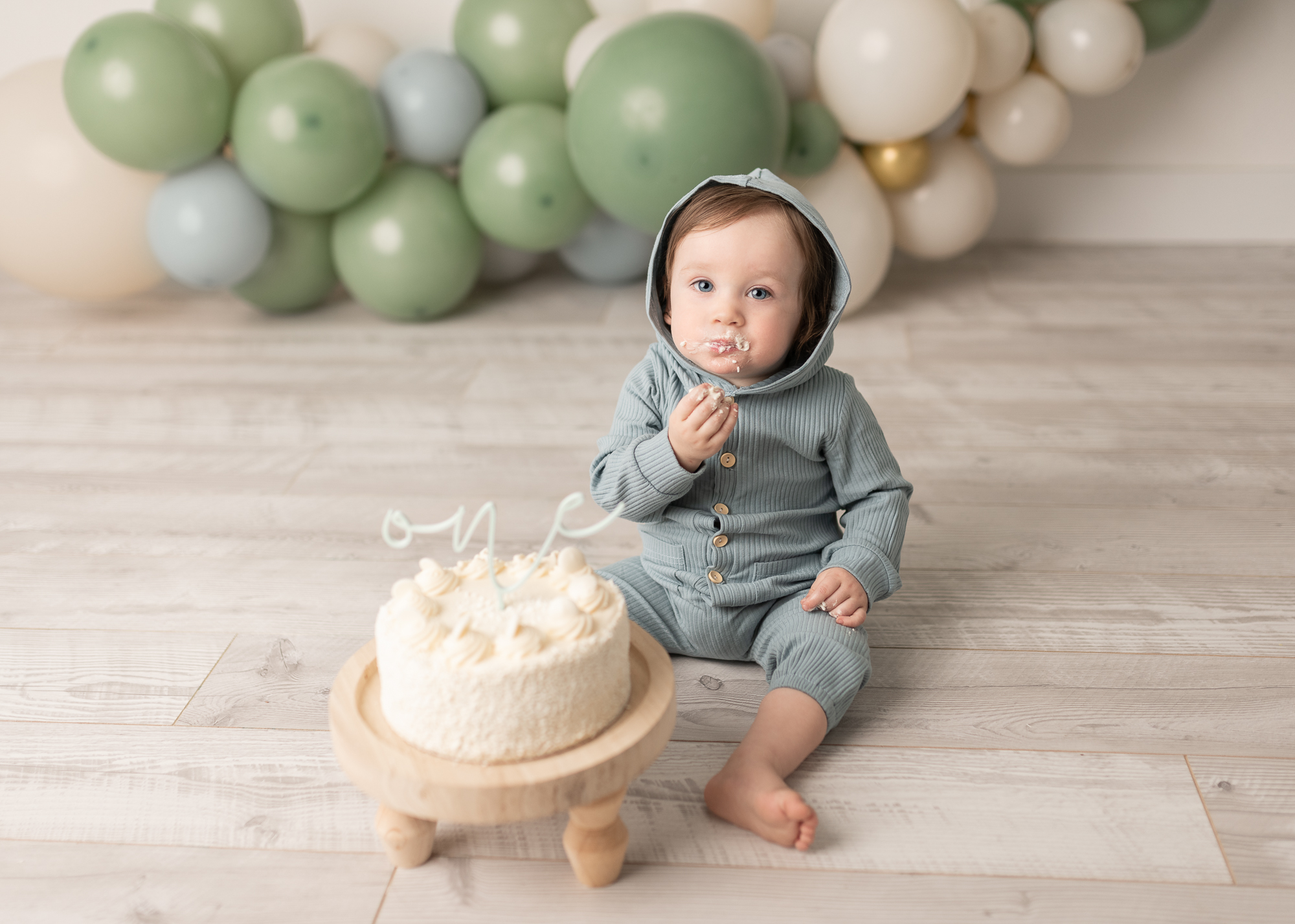 Little boy in a onesie eating cake