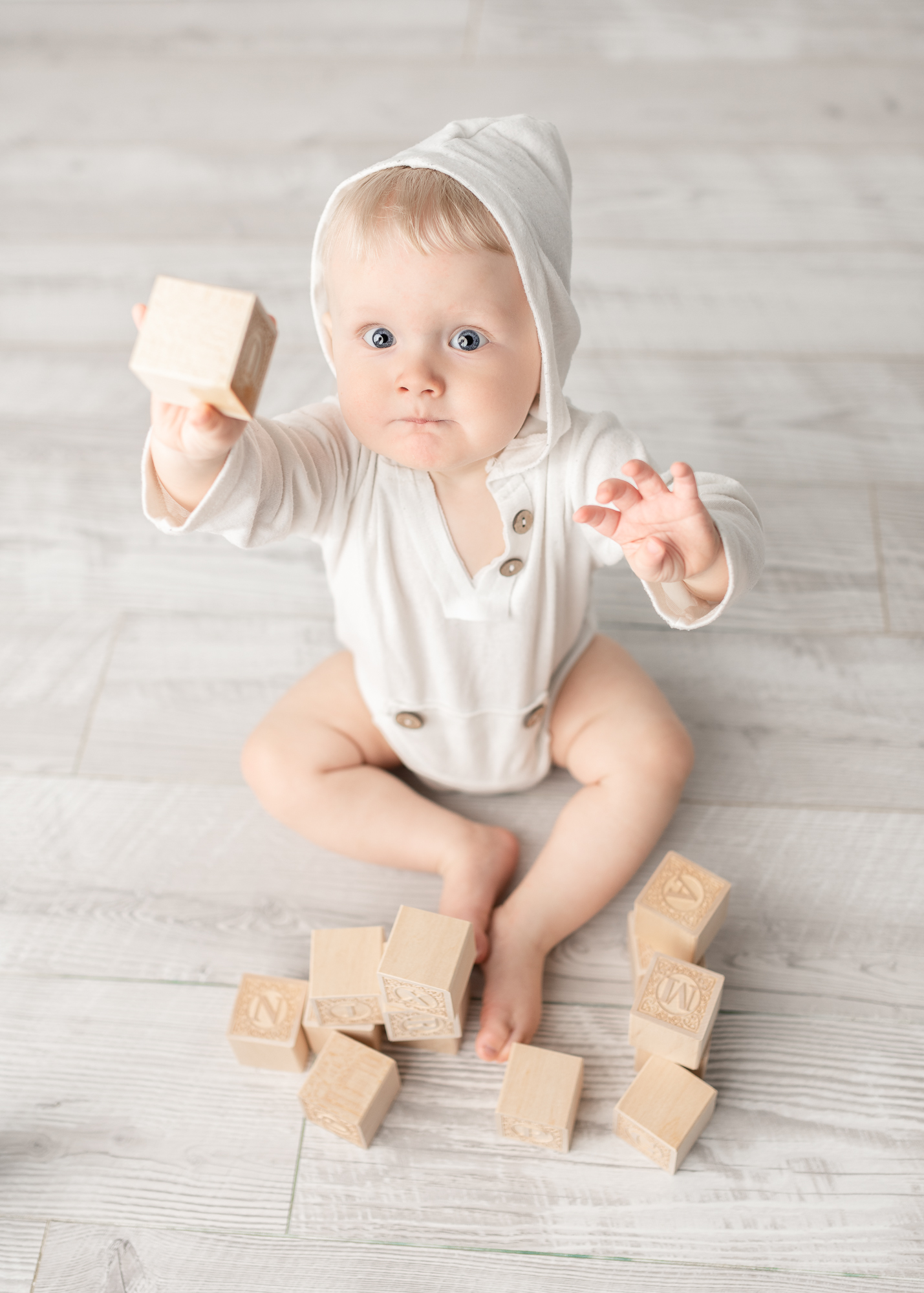 little boy in white hoodie holding on to blocks