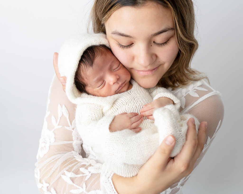 New mom snuggling her newborn baby both dressed in white Maternal Fetal Medicine Clinic