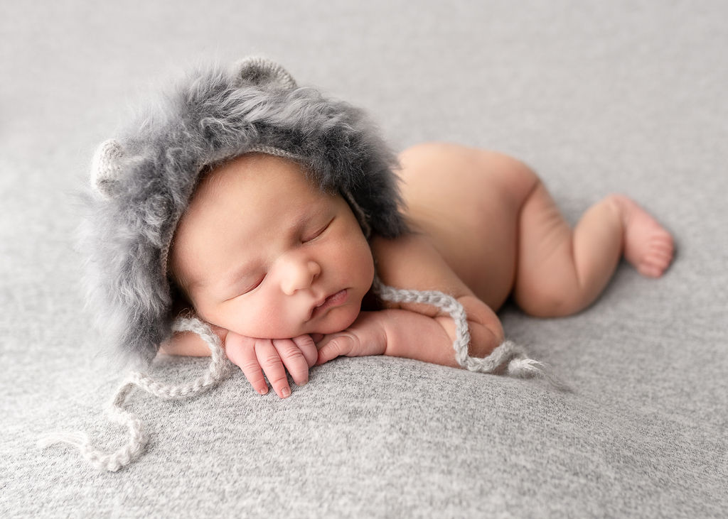 newborn in grey fur cap sleeping on a grey blanket Maternal Fetal Medicine Clinic