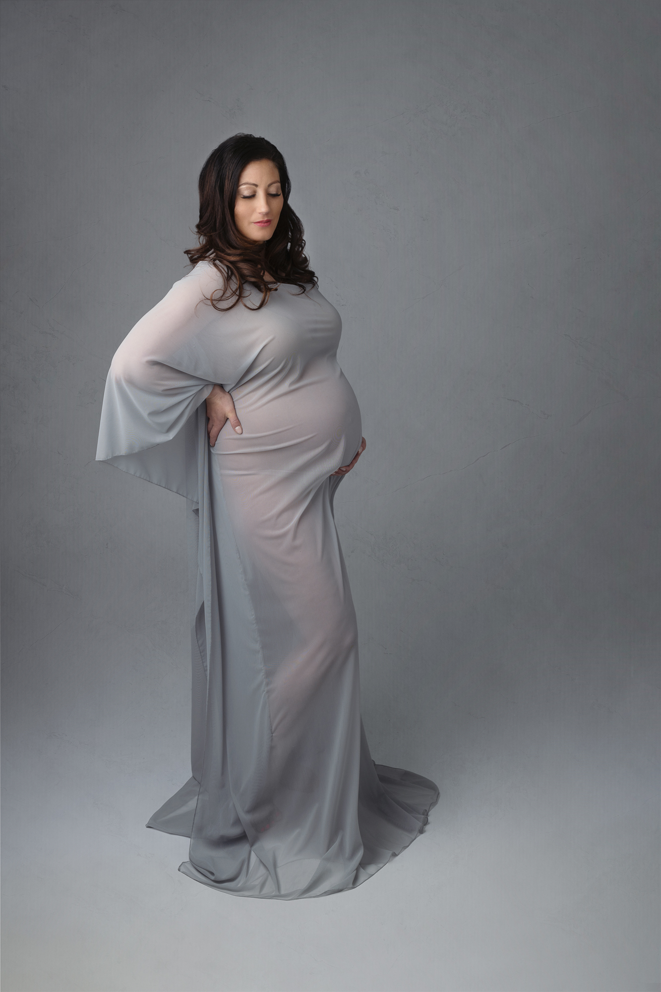 Pregnant mom in grey sheer gown holding her back and bump Siskiyou Massage