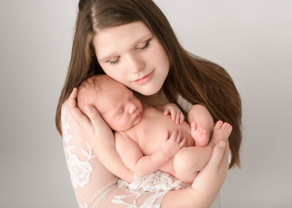 new mom holding her newborn baby in her arms in a studio