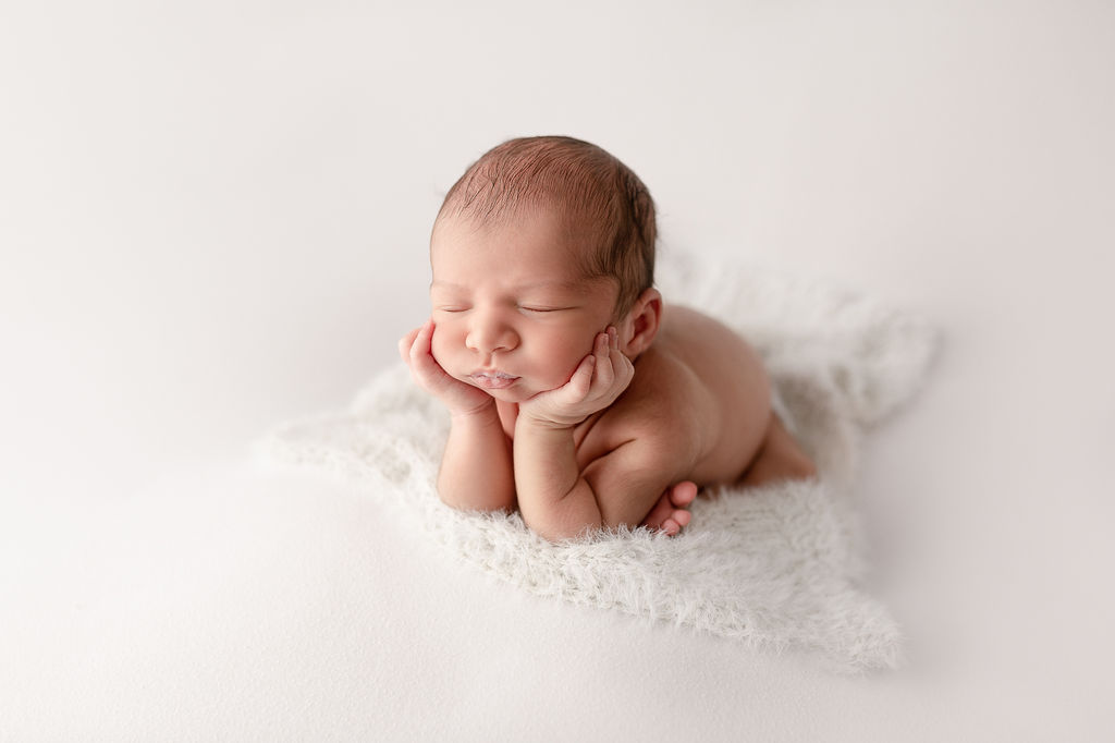newborn baby laying on a white blanket with it's head on it's hands Sanford Clinic Klamath Falls