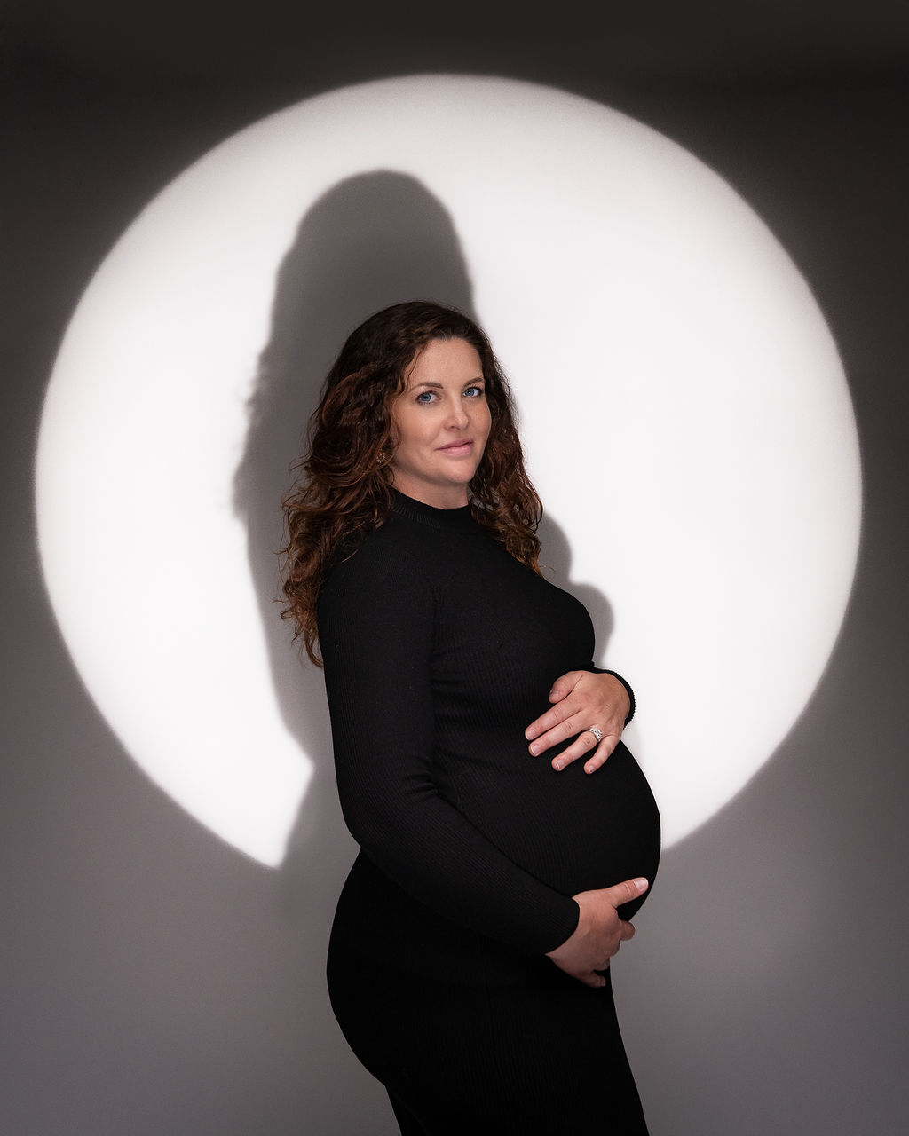 pregnant woman in black long sleeve maternity gown with a spotlight on her Siskiyou Vital Medicine