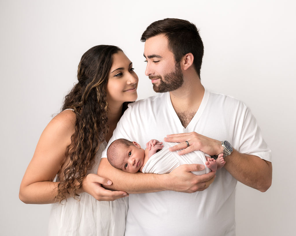 new mom and dad holding their newborn baby wrapped in white Southern Oregon Pediatrics