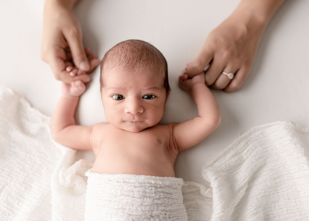 newborn baby with a cloth blanket holding their parent's hands with their eyes open Dr. Cherry Klamath Falls