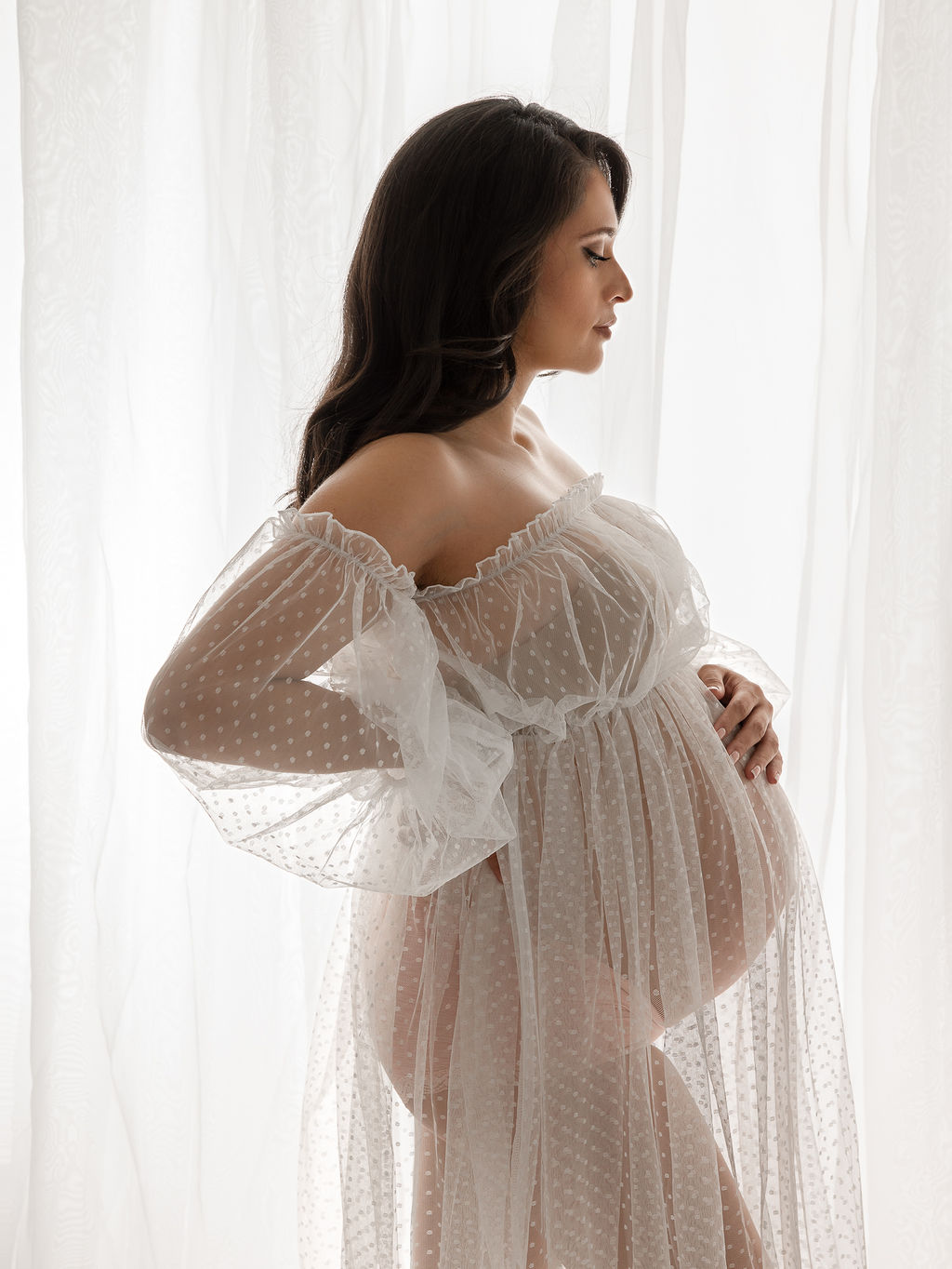 pregnant woman in sheer gown standing near a window Central Oregon OB-GYN