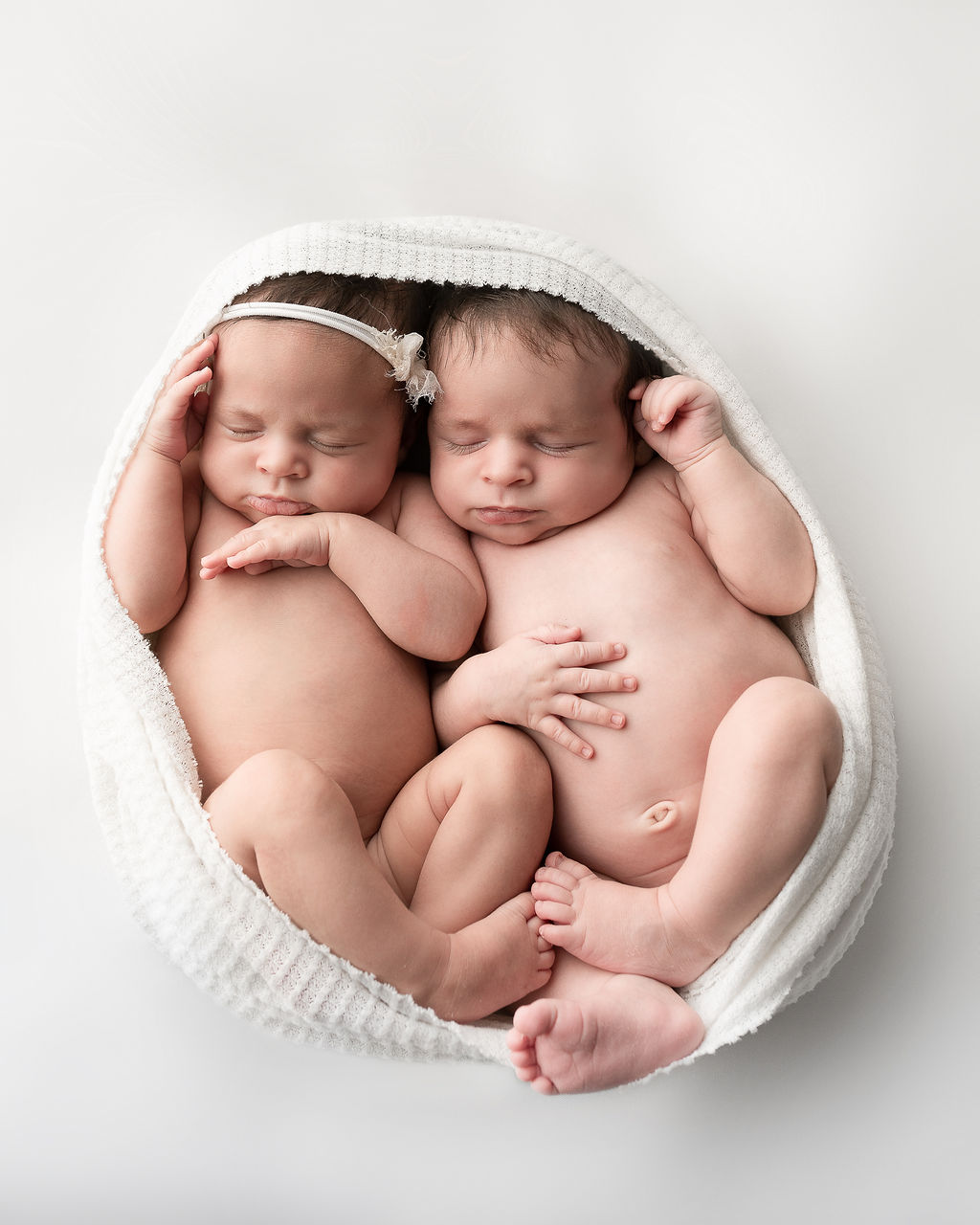 newborn twins cuddled in a white wrap