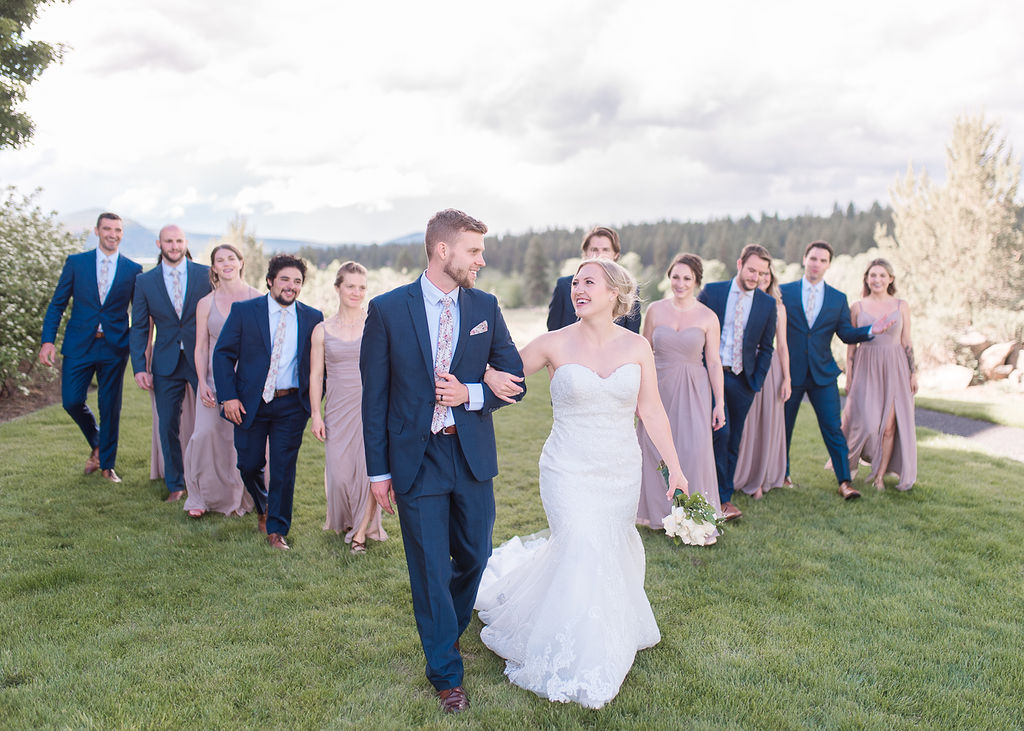 bride and groom walking through a field with their wedding party in navy and lavendar Southern Oregon Wedding Venues