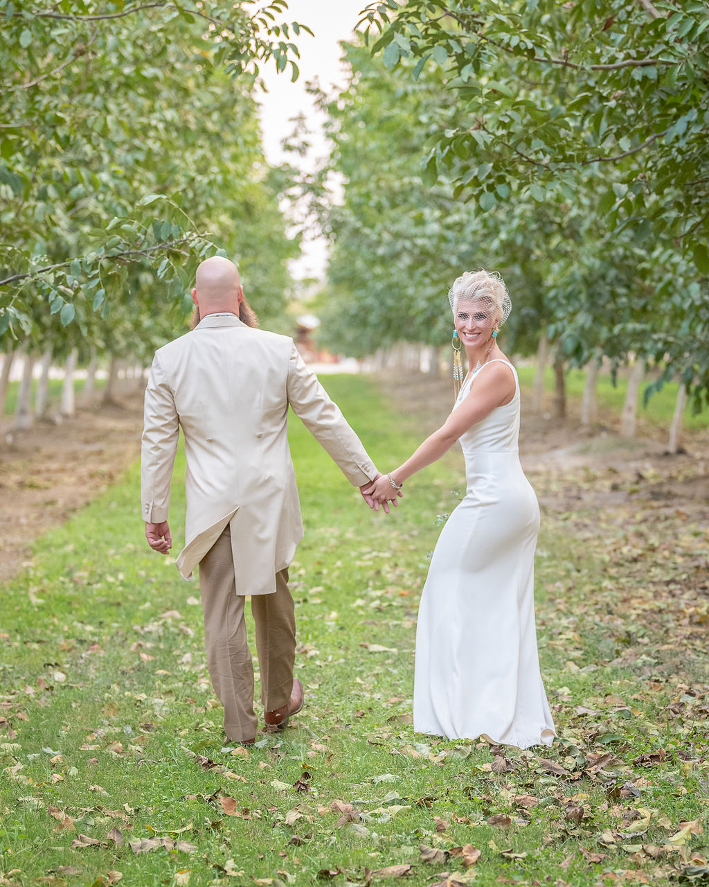 bride and groom walking through a vineyard at Southern Oregon Wedding Venues with the bride looking back