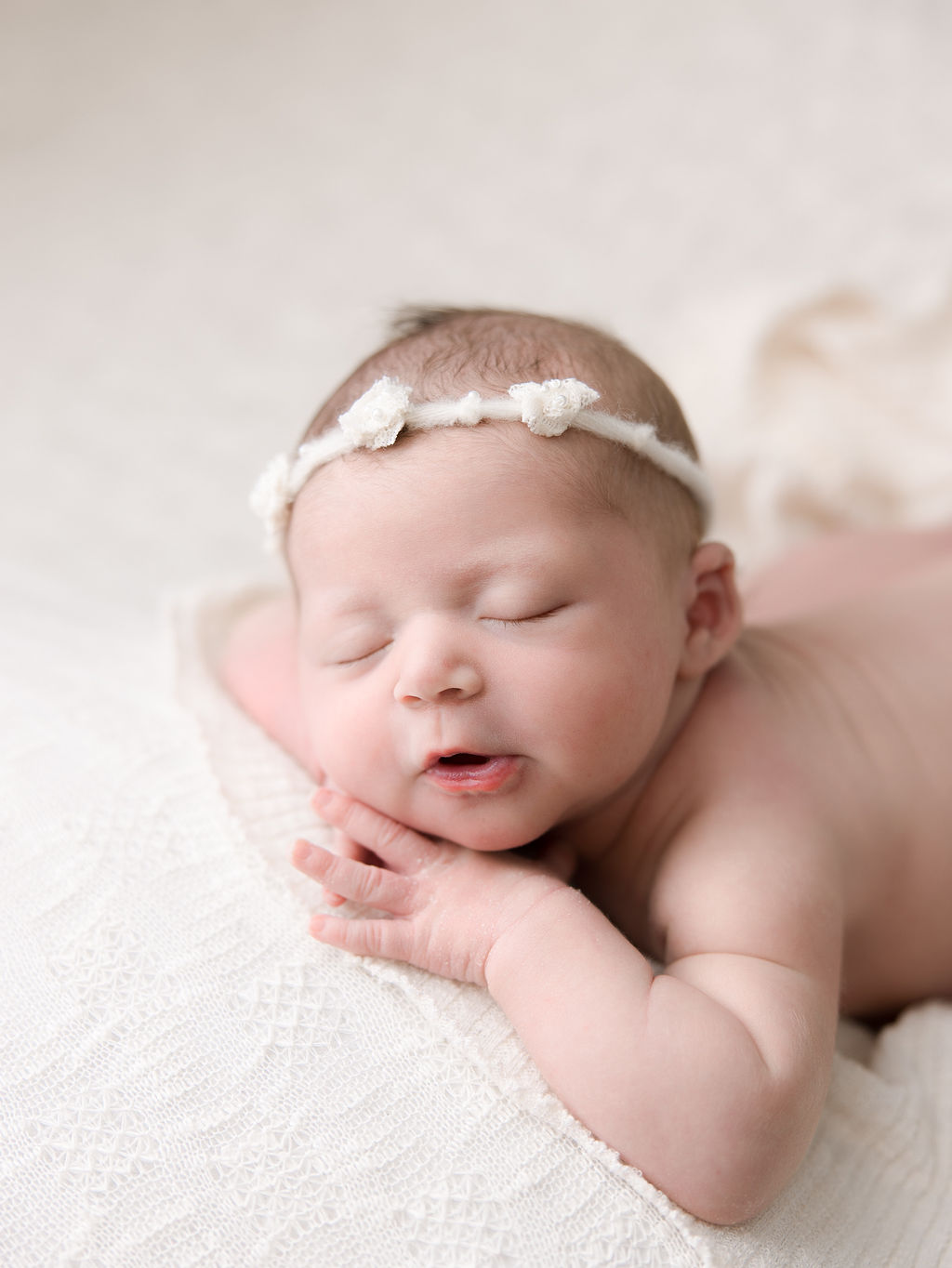 newborn baby girl sleeping on her hands with a flower headband in her hair St. Charles Birthing Center